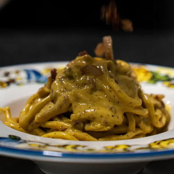 盛在彩绘陶瓷盘中的新鲜 bigoli 意面 – L'Angolo di Cavour，维罗纳